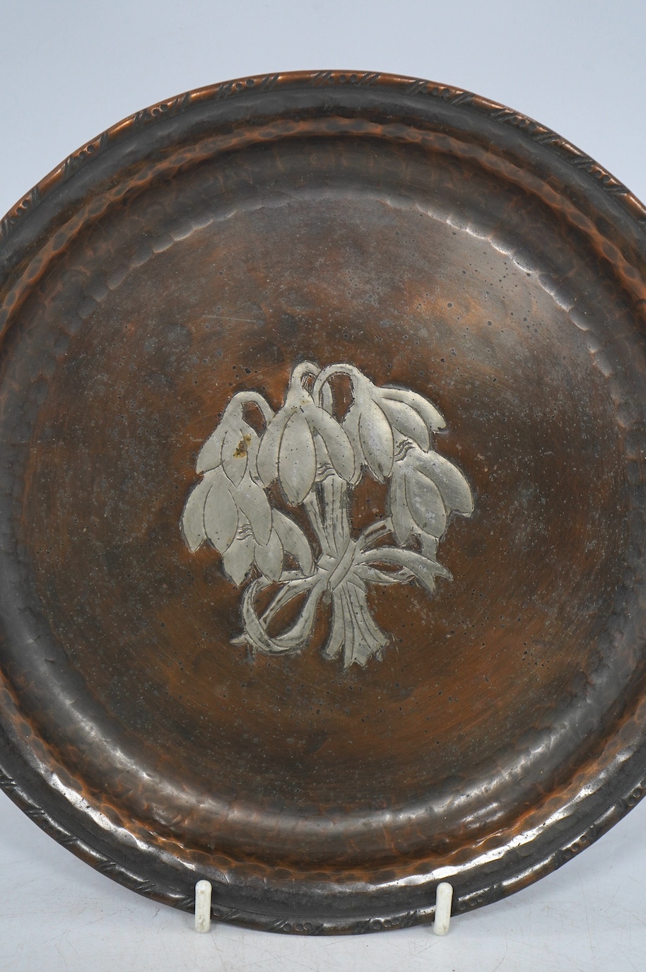 A Hugh Wallis Arts & Crafts small copper and pewter tray decorated with snowdrops, stamped HW, diameter 19.5cm. Condition - fair
